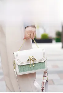 Détail du sac bandoulière blanc et vert avec breloque cygne doré et sangle brodée