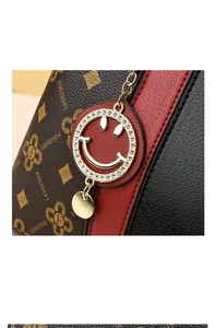 Détail du sac à main bicolore avec pendentif smiley en strass et texture en cuir PU