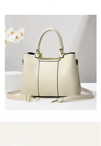 Macro shot of cream handbag showing lychee leather texture and gold hardware detail