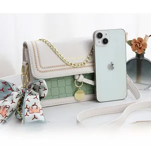 Contrast color crossbody bag shown next to a smartphone to demonstrate the small size