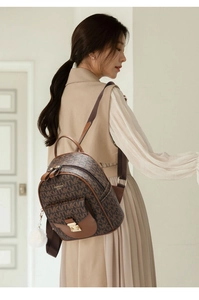 Detail of a brown monogram backpack featuring gold hardware and a white fur ball pendant
