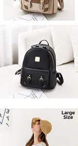Détail d'un sac à dos noir en similicuir avec logo doré et breloque pompon blanc doux