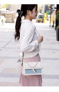 Detail of elegant two-tone leather crossbody bag with silk scarf and heart metal charm