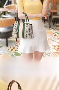 Détail des rayures contrastées et de l'imprimé monogramme sur le sac à main beige