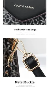 Detail of embossed black leather handbag with gold logo and premium metal buckles