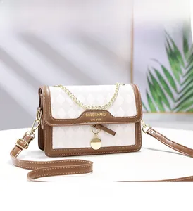 Detail of a quilted crossbody bag with a gold chain and contrast trim in cream and brown