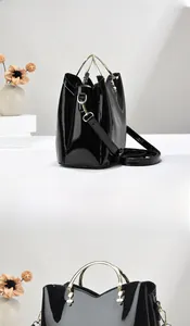 Vue détaillée du sac noir verni avec poignées dorées circulaires et bandoulière