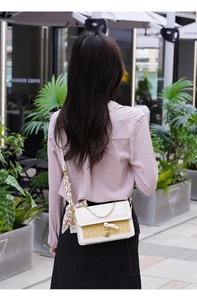 Detail of yellow plaid crossbody bag with silk scarf handle and gold chain accessory