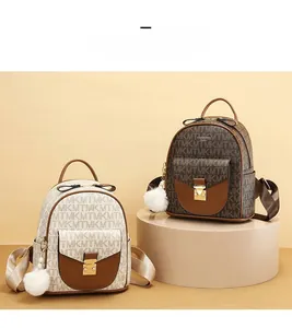 Detail view of mini backpacks in cream and brown with monogram patterns and fur ball charms