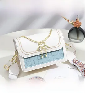 Détail du sac bandoulière avec pendentif cygne, chaîne dorée et sangle à motif floral