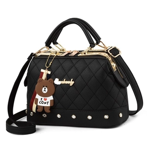 Black quilted leather Boston handbag with gold studs and a character charm on white background