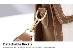 Detail of detachable gold metal buckle and brown leather strap on a quilted bag