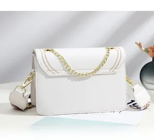 Détail du sac bandoulière en cuir blanc avec chaîne et sangle tissée brodée élégante