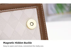 Detail view of the magnetic snap closure on a textured white fabric and leather crossbody bag