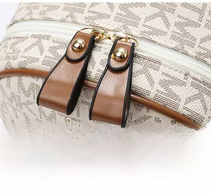 Detail of the dual golden zippers with brown leather pulls on the MK monogram backpack
