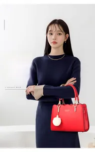 Dettaglio della borsa a mano rossa in pelle PU con bordi ondulati e pompon decorativo