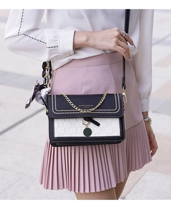 Detail of black and white crossbody bag with woven texture and decorative silk scarf