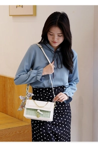 Detail of color-block flap bag with green checkered fabric and silk scarf on handle