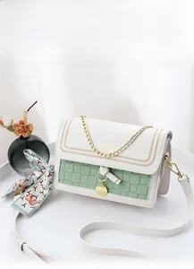 Detail of white leather and green checkered bag with gold chain and floral scarf accessory