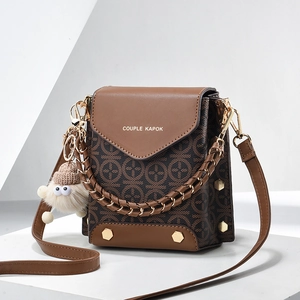 Brown monogram crossbody bag with gold hardware and plush charm on white stand