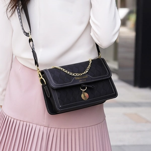 Black quilted crossbody bag with white stitching and gold chain strap in street style