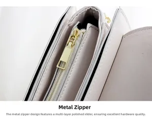 Detail of polished gold zipper and fine stitching on a premium beige leather crossbody bag