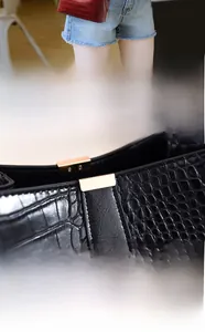 Detail of elegant gold magnetic buckle on crocodile pattern leather bucket bag