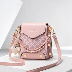 Pink fashion crossbody bag with geometric print and decorative fuzzy monster charm