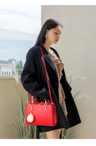Dettaglio borsa rossa in pelle PU con bordi ondulati e ciondolo a pompon bianco