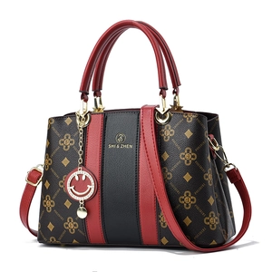 Sac à main bicolore avec motif floral, poignées rouges et bandoulière réglable