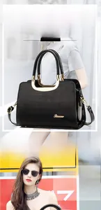 Macro shot of glossy black leather tote featuring U-shaped hardware and fine texture