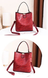 Detail of red crocodile texture bucket bag with gold hardware and black handle