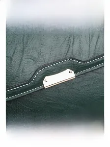 Détail du sac à main en cuir vert foncé avec garniture dorée et surpiqûres blanches
