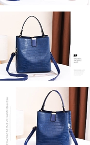 Detailed view of blue crocodile pattern bucket bag with golden metal buckle and top handle