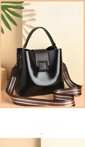 Close-up of retro black bucket bag with brown flap and colorful woven shoulder strap
