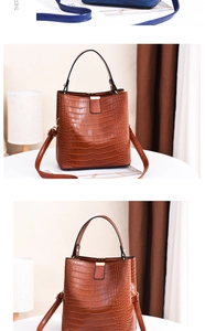 Detail of crocodile embossed leather bucket bag showing sturdy handle and shoulder strap
