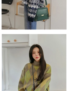 Détail du sac à bandoulière en cuir vert foncé avec boucle dorée sur un pull en maille
