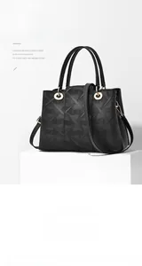 Detail der schwarzen geprägten Ledertasche mit geometrischer Textur und goldener Hardware