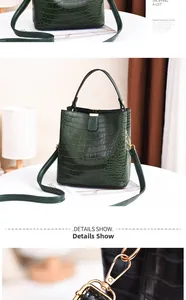 Detail of dark green crocodile texture bucket bag with gold hardware and top handle
