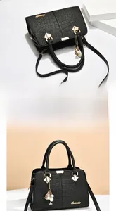 Close-up of black crocodile pattern faux leather handbag with golden hardware and pearl tassel