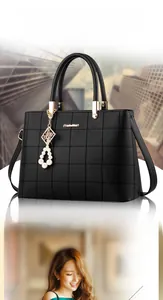Close-up of black embroidered lattice tote bag with golden hardware and pearl charm detail