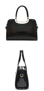 Close-up of black glossy leather handbag featuring textured embossing and golden metal hardware