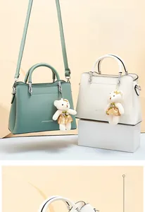 Detail of dark green and ivory white faux leather handbags with cute bear charms
