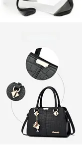 Detail view of black crocodile pattern Boston bag with gold hardware and smooth zippers