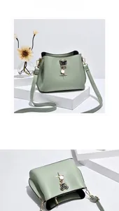 Detail view of mint green bucket bag with gold bear charm and top opening perspective