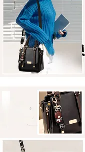 Detail of black leather handbag featuring contrast brown handle and cute bear charm