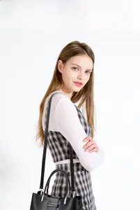 Detail of a black leather handbag featuring silver hardware and adjustable shoulder strap
