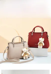 Detailed view of beige and wine red soft leather handbags with cute bear pendants