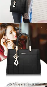 Close-up of black quilted leather handbag with gold logo and pearl charm detail