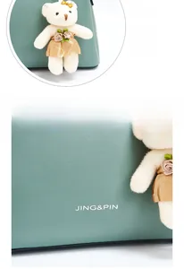 Detail of Morandi green leather texture and plush bear charm with silver logo imprint